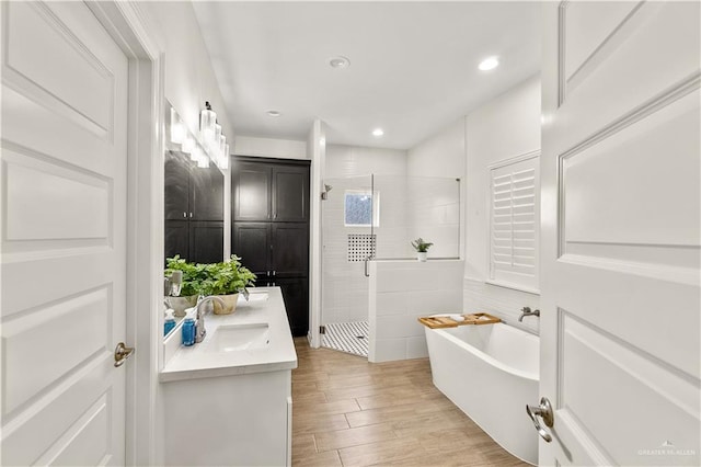 16593 W Mccullar Ct, Harlingen, TX 78552 - bathroom featuring a stall shower, double vanity, a freestanding tub, wood finished floors, and recessed lighting