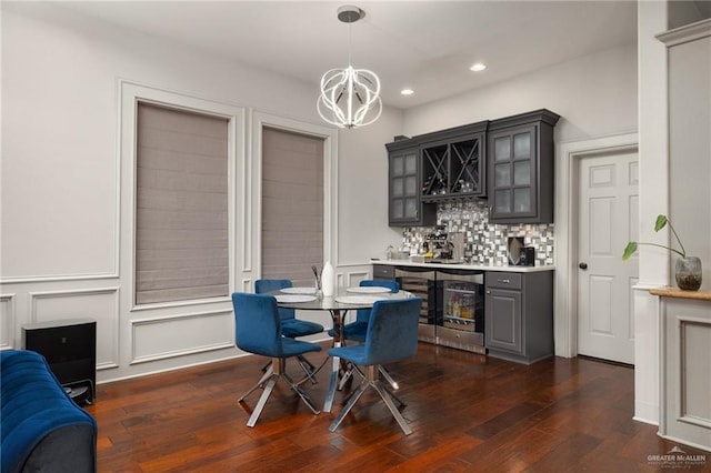 dining space featuring dark hardwood / wood-style floors, beverage cooler, bar area, and a chandelier