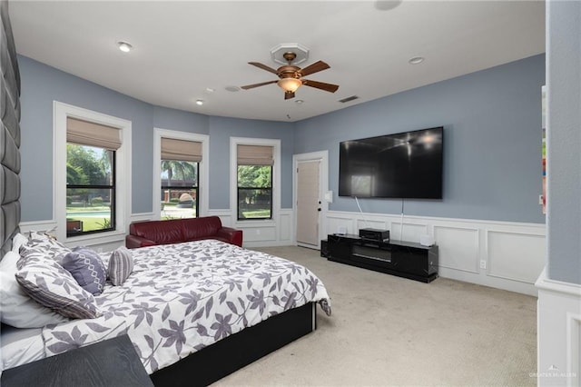 bedroom featuring multiple windows, light carpet, and ceiling fan