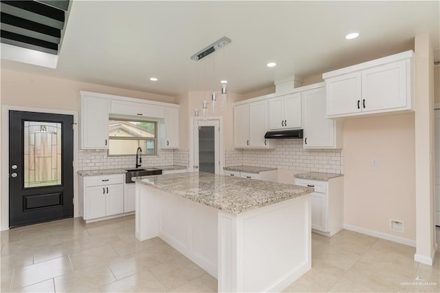 kitchen with white cabinets, sink, a kitchen island, and hanging light fixtures