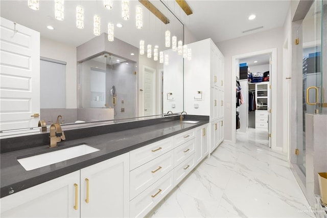 full bath with a sink, a walk in closet, double vanity, and marble finish floor