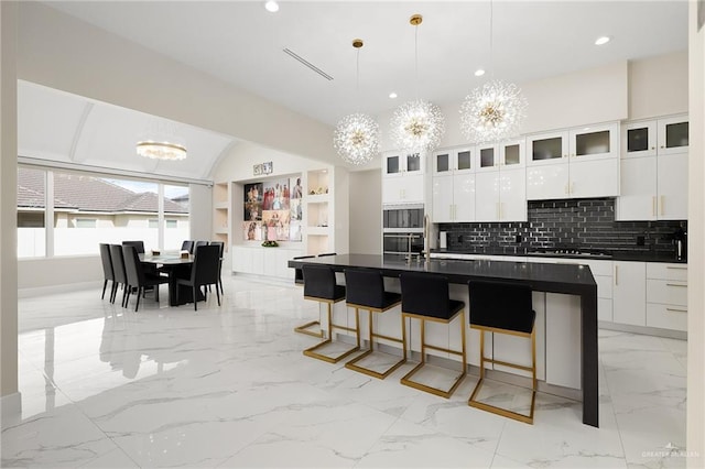 kitchen with dark countertops, decorative light fixtures, white cabinets, a notable chandelier, and glass insert cabinets