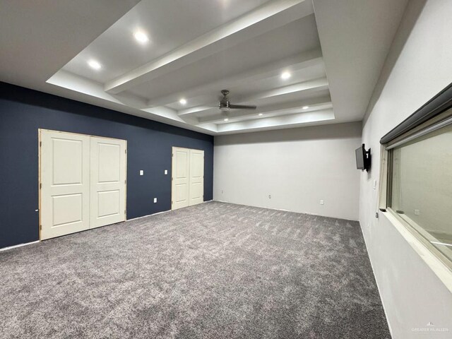 spare room featuring beamed ceiling, carpet floors, ceiling fan, and a tray ceiling