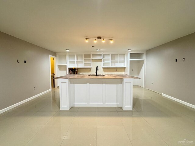 kitchen with white cabinetry, sink, and light tile patterned floors