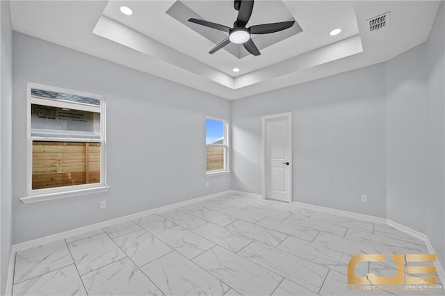 empty room featuring ceiling fan and a tray ceiling