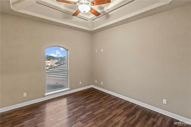 spare room with dark hardwood / wood-style flooring, a raised ceiling, and ceiling fan