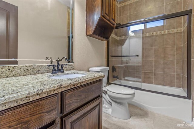 full bathroom with tile patterned floors, vanity, toilet, and shower / bath combination with glass door