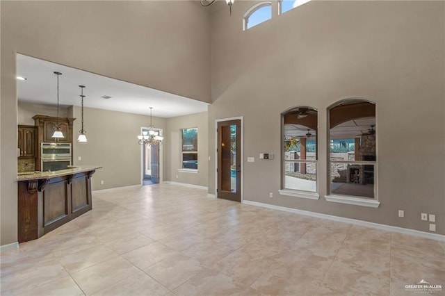 interior space with a towering ceiling, a healthy amount of sunlight, and ceiling fan with notable chandelier