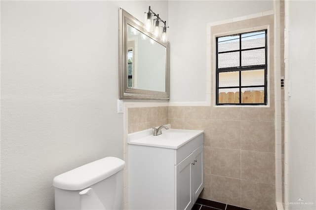 bathroom with tile patterned flooring, vanity, toilet, and tile walls