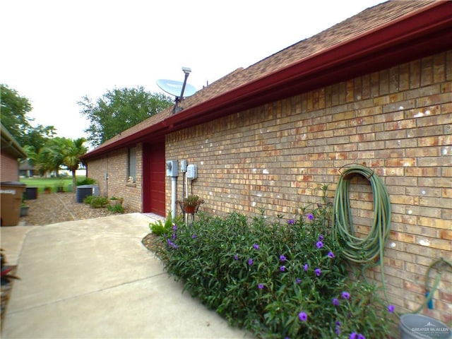 3319 Country Club Dr N, Edinburg, TX 78542 - view of side of home with brick siding, central AC, a shingled roof, concrete driveway, and a garage