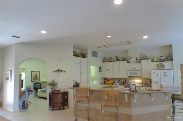 3319 Country Club Dr N, Edinburg, TX 78542 - kitchen featuring white appliances, arched walkways, a kitchen bar, white cabinetry, and recessed lighting