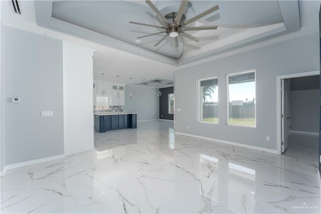 unfurnished living room with ceiling fan and a raised ceiling