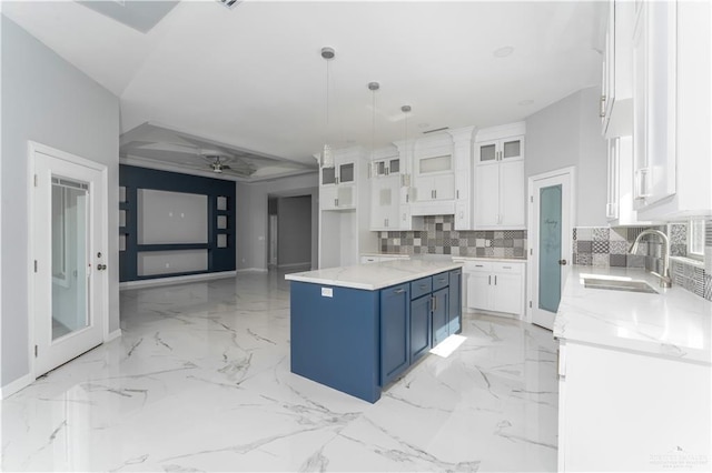 kitchen with a center island, sink, hanging light fixtures, blue cabinetry, and white cabinetry