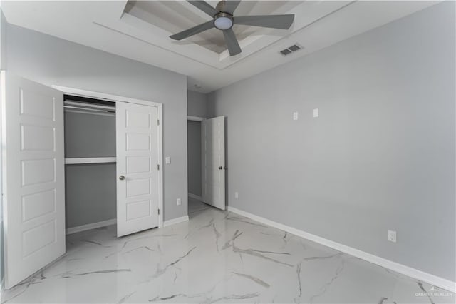 unfurnished bedroom featuring a closet, ceiling fan, and a tray ceiling