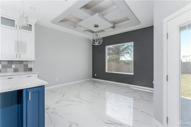 unfurnished dining area with a notable chandelier, a wealth of natural light, and coffered ceiling