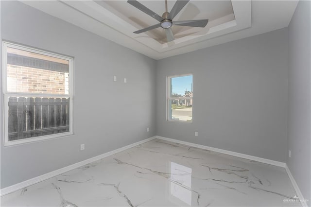 unfurnished room with ceiling fan and a raised ceiling