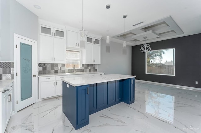 kitchen with backsplash, light stone countertops, decorative light fixtures, a kitchen island, and white cabinetry