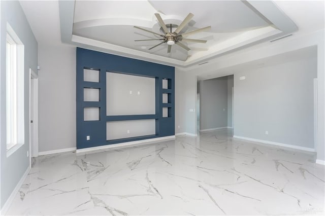 foyer featuring a raised ceiling and ceiling fan