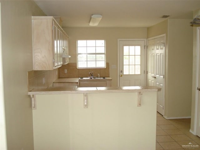 719 W Sherryl Ave, Pharr, TX 78577 - kitchen with a peninsula, a sink, tile counters, and a kitchen bar