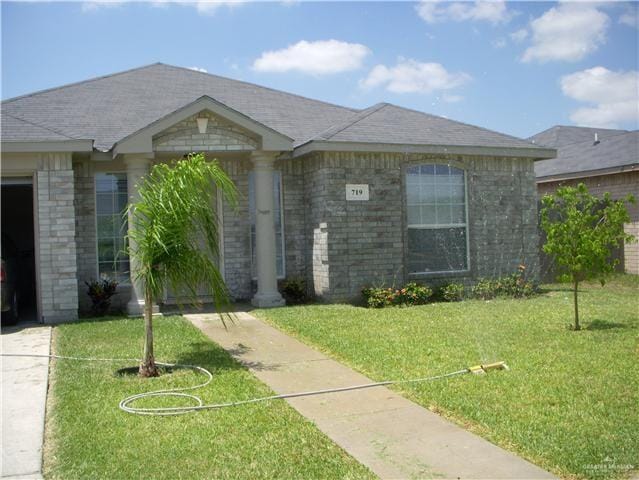 view of front of property featuring a front lawn and roof with shingles