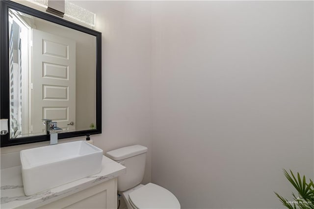 half bath featuring vanity and toilet