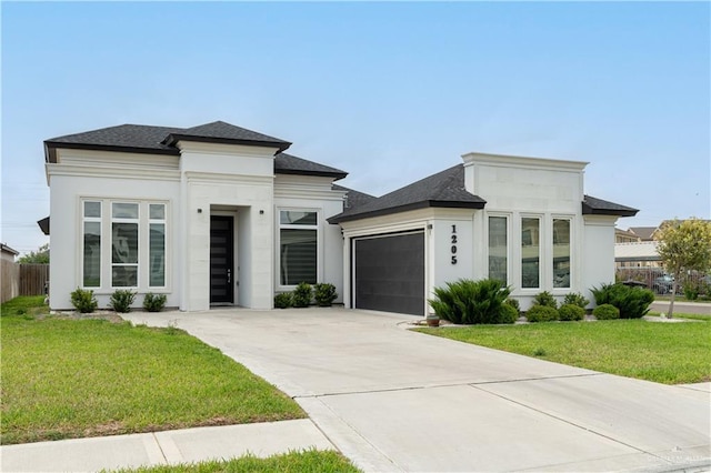prairie-style house featuring a garage, a front lawn, concrete driveway, and stucco siding