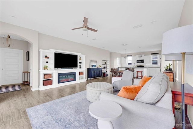 5237 Lost Creek Ln, Mcallen, TX 78504 - living room with ceiling fan, light wood-style floors, arched walkways, and a glass covered fireplace