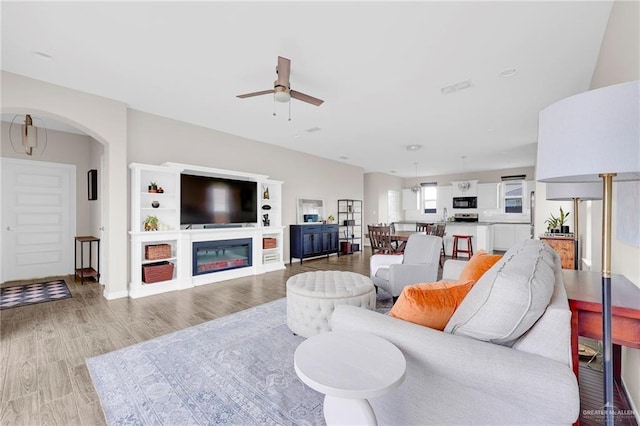 5237 Lost Creek Ln, Mcallen, TX 78504 - living room with a ceiling fan, light wood-type flooring, arched walkways, and a glass covered fireplace