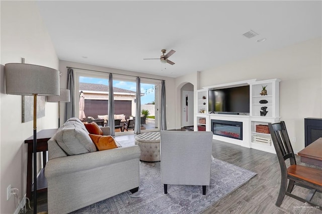 5237 Lost Creek Ln, Mcallen, TX 78504 - living room with a glass covered fireplace, arched walkways, ceiling fan, and wood finished floors