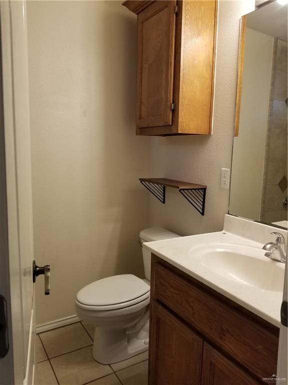 bathroom featuring tile patterned flooring, vanity, toilet, and a shower