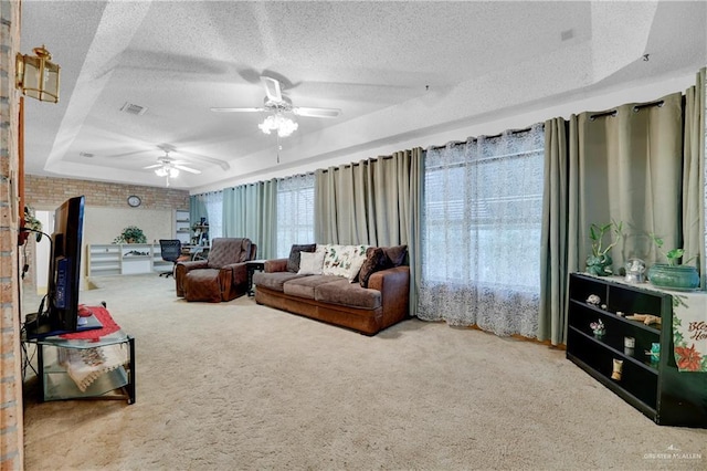 living room with carpet flooring, ceiling fan, a textured ceiling, and a tray ceiling