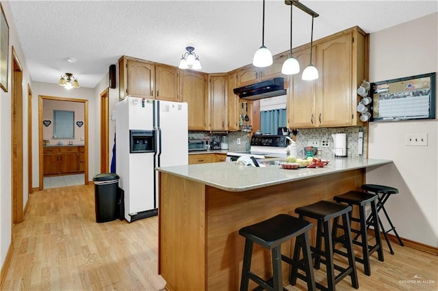 kitchen featuring pendant lighting, a breakfast bar, white appliances, tasteful backsplash, and kitchen peninsula