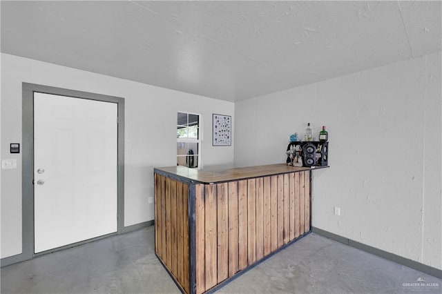 bar with baseboards, a bar, and concrete flooring