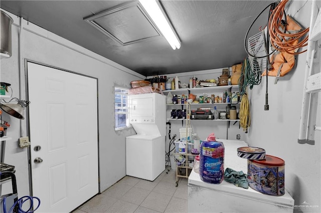 clothes washing area featuring attic access, stacked washer and dryer, light tile patterned flooring, and laundry area
