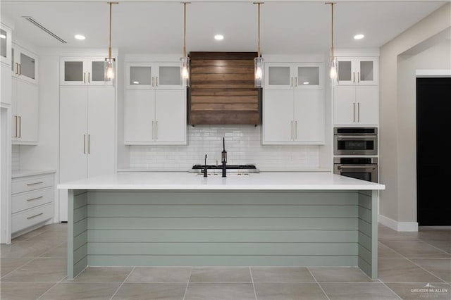 1426 Kalob Cir, Harlingen, TX 78552 - kitchen featuring an island with sink, decorative backsplash, white cabinetry, light countertops, and light tile patterned floors