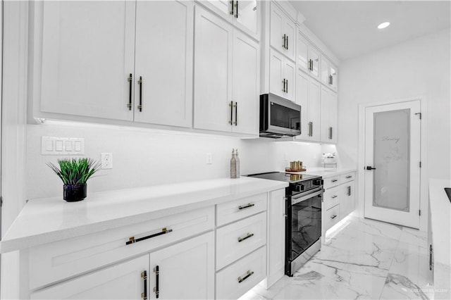 kitchen with stainless steel microwave, marble finish floor, range with electric stovetop, recessed lighting, and white cabinets