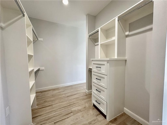 walk in closet with light hardwood / wood-style floors