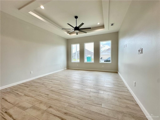 unfurnished room featuring light hardwood / wood-style floors, a raised ceiling, and ceiling fan