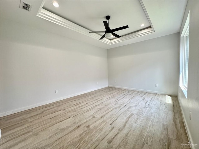 spare room with a raised ceiling, ceiling fan, and light hardwood / wood-style floors