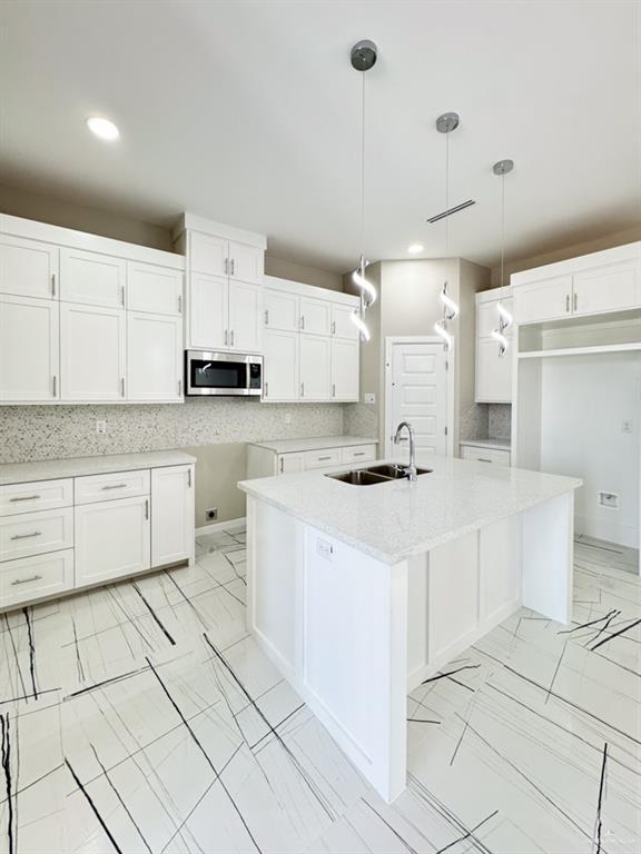 kitchen featuring hanging light fixtures, sink, and white cabinets