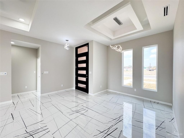 entrance foyer featuring a raised ceiling and an inviting chandelier