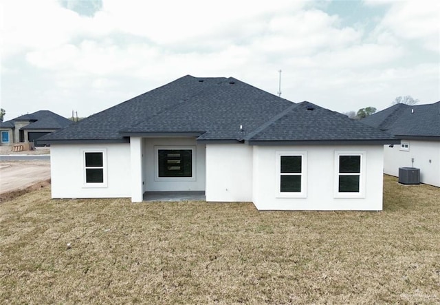 back of property with central AC unit and a lawn