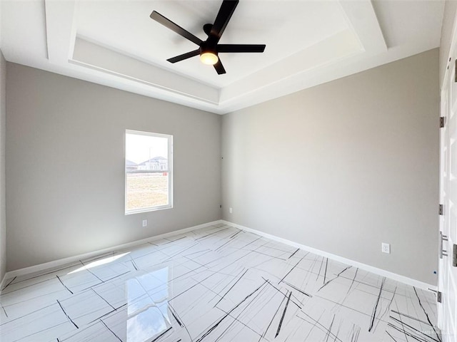 spare room with a raised ceiling and ceiling fan