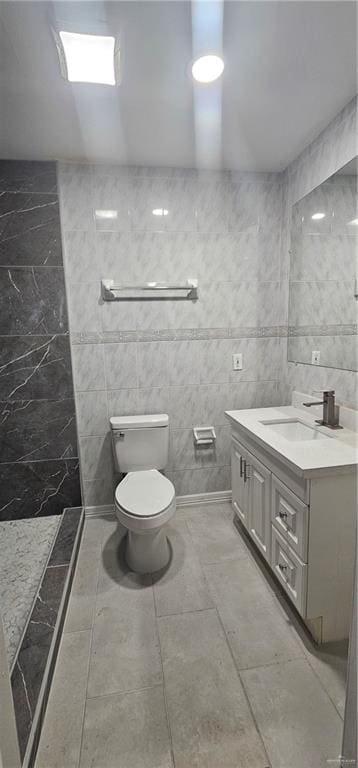 bathroom with vanity, tile walls, and toilet