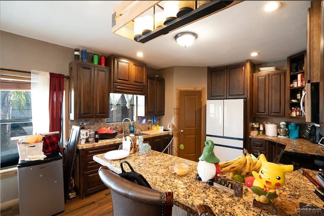 kitchen with sink, a breakfast bar area, a healthy amount of sunlight, and white fridge