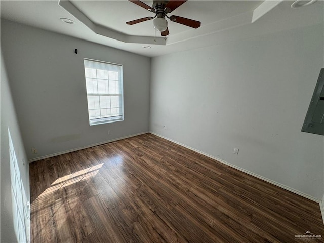 unfurnished room with dark hardwood / wood-style floors, ceiling fan, and a tray ceiling