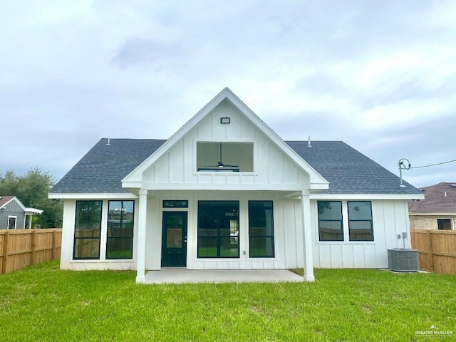 rear view of property featuring a shingled roof, board and batten siding, fence, and a yard