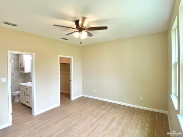 unfurnished bedroom with visible vents, a walk in closet, and light wood-type flooring