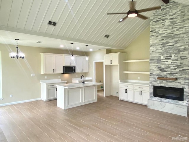 kitchen with visible vents, open floor plan, stainless steel microwave, a sink, and ceiling fan with notable chandelier