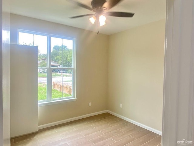 unfurnished room featuring plenty of natural light, a ceiling fan, baseboards, and light wood-type flooring